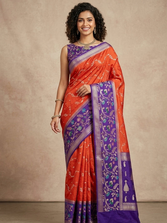 A woman modeling a bright orange and purple Banarasi silk saree with intricate floral patterns and a matching purple blouse, set against a neutral beige studio backdrop.