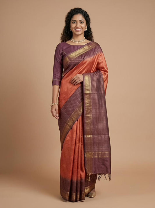 A woman modeling a traditional Indian saree with a deep purple blouse and a matching purple and orange saree body featuring gold zari metallic borders, set against a solid beige studio background.